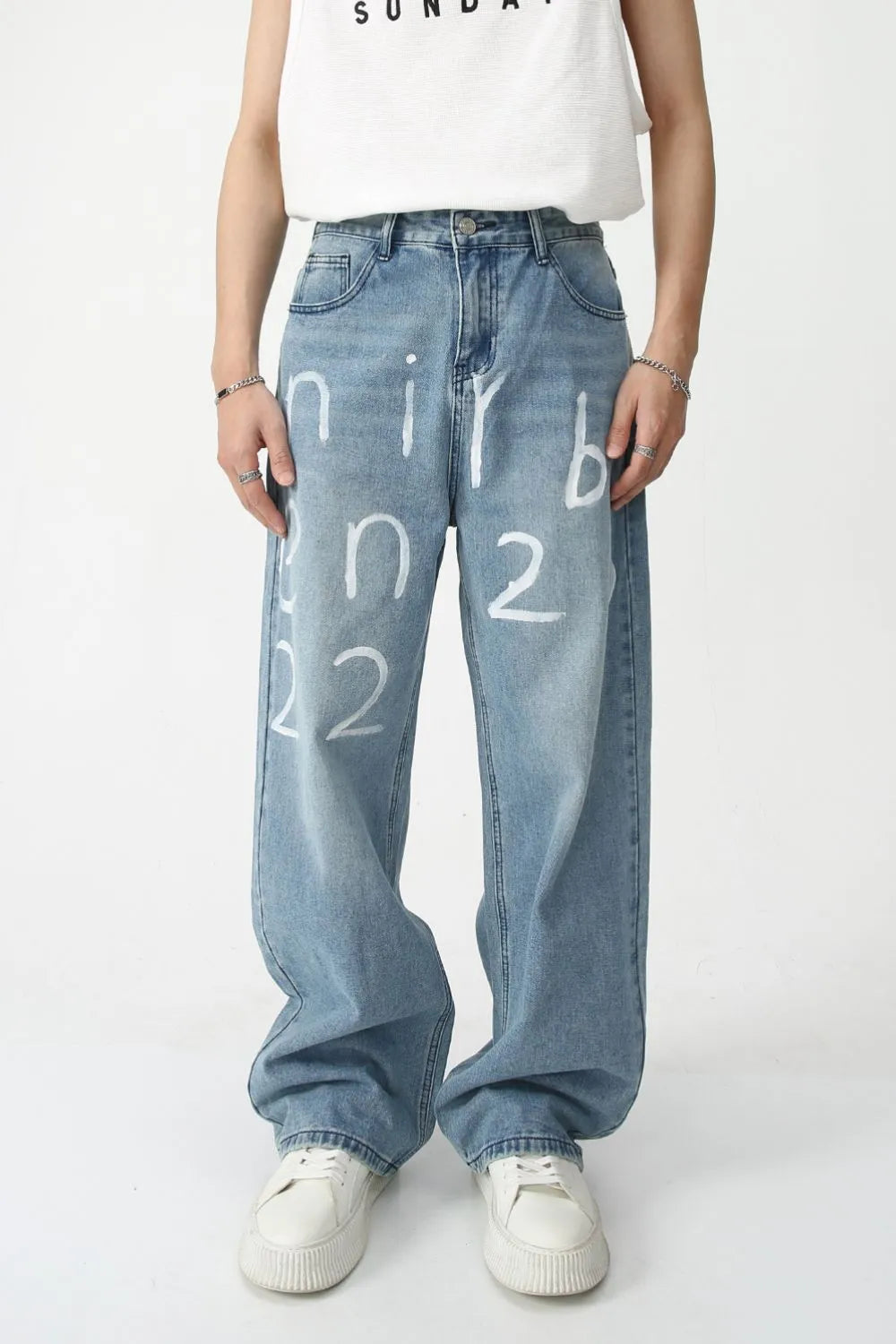 Painted script baggy jeans in medium wash denim with a loose fit and artistic white lettering.