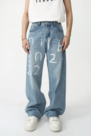 Painted script baggy jeans in medium wash denim with a loose fit and artistic white lettering.