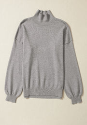 Gray knit sweater with mock neck and balloon sleeves.