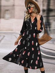 Black midi dress with feather print, V-neck, tiered skirt, and button front.