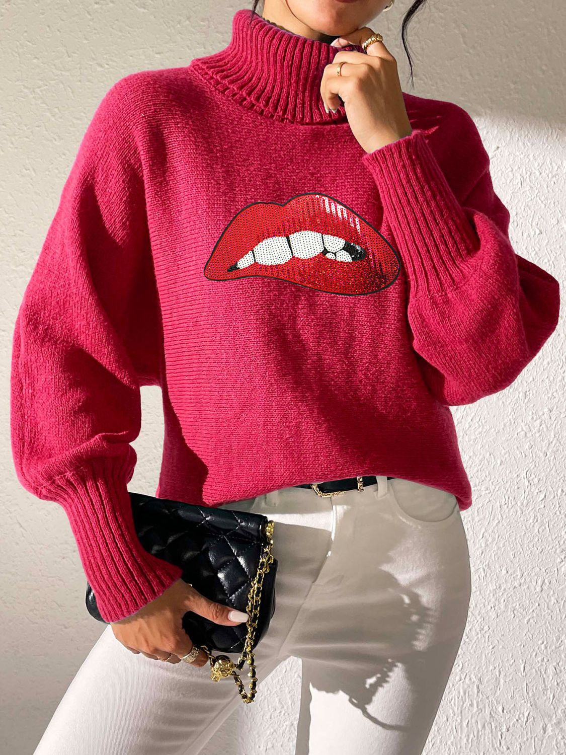Pink turtleneck sweater with sequin lip graphic and balloon sleeves.