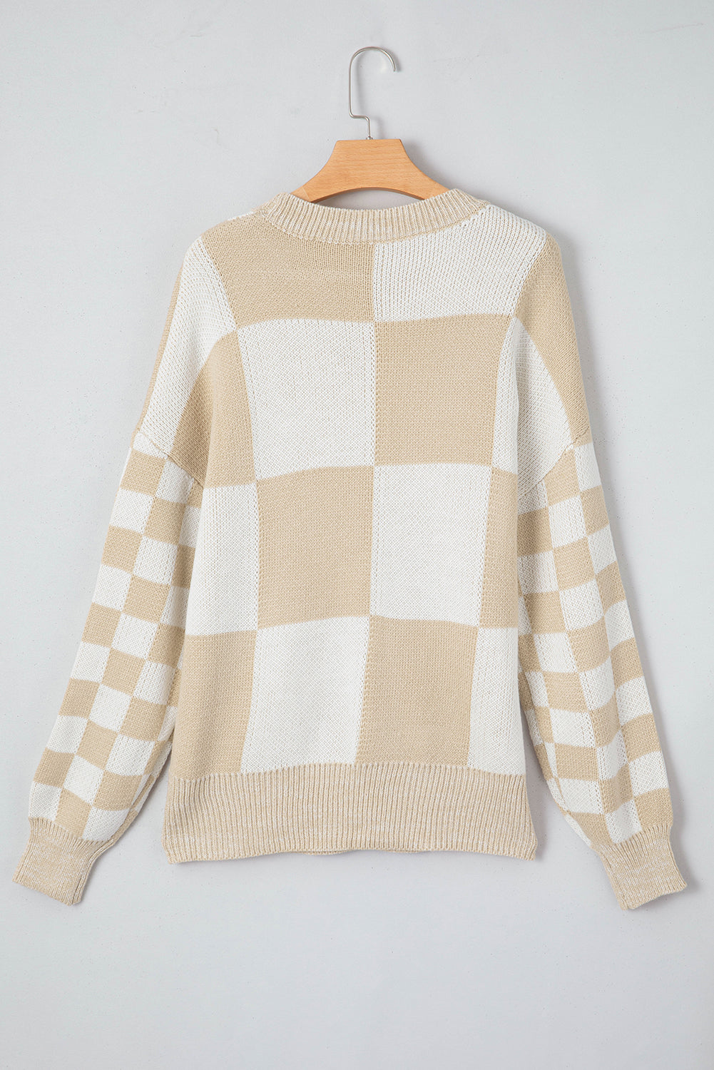Beige and white checkerboard knit sweater with crewneck and long sleeves.