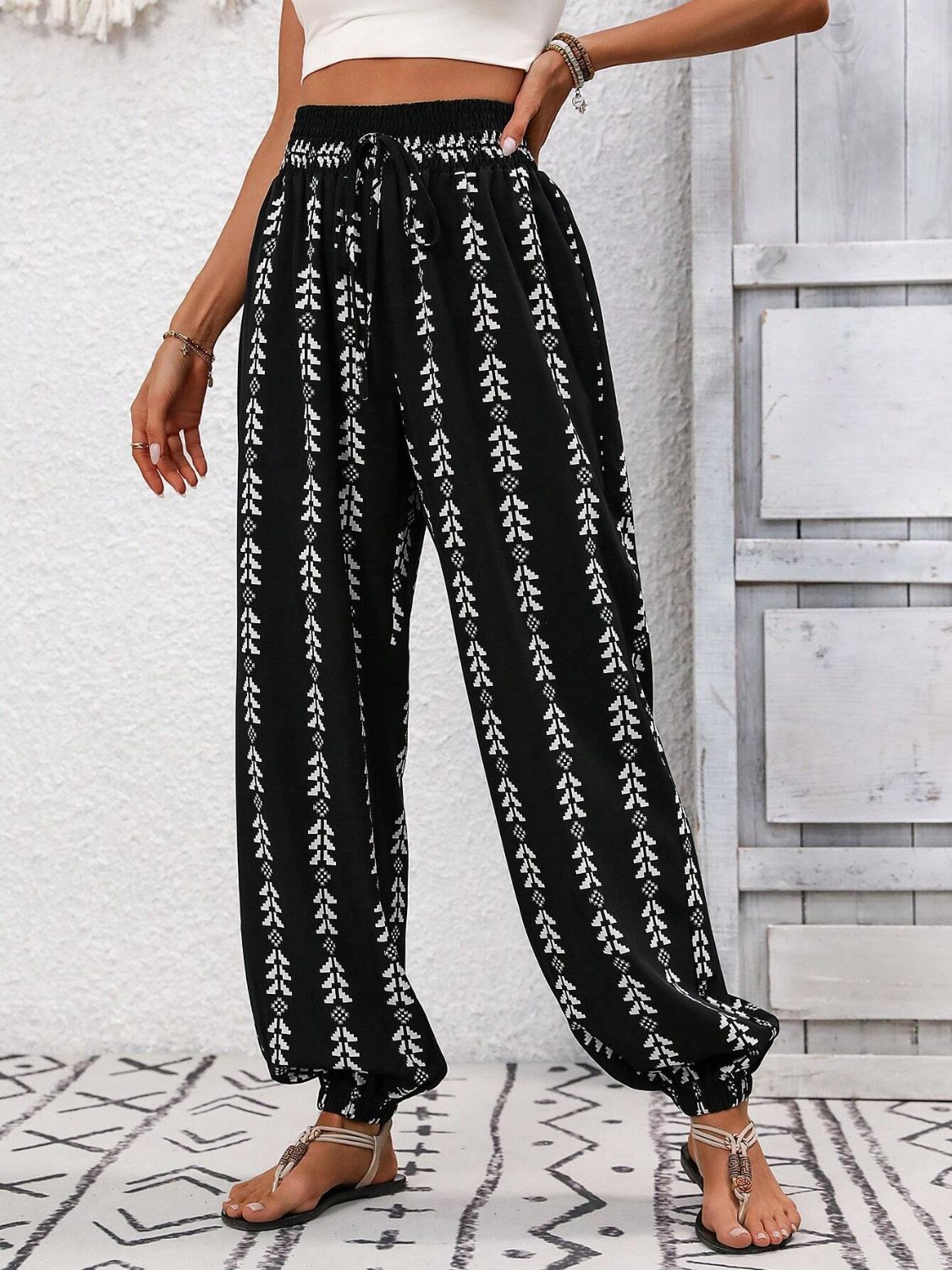 Black ankle trousers with white leaf print, gathered waist and cuffs.