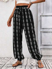 Black ankle trousers with white leaf print, gathered waist and cuffs.
