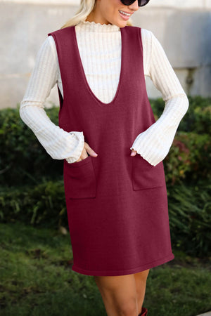 Burgundy knit sweater dress with deep V-neck and front pockets, layered over a white ribbed turtleneck.