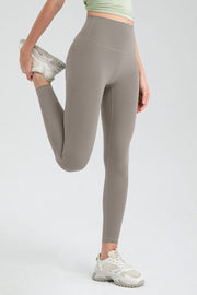 Taupe high rise leggings with a seamless waistband, shown in a stretching pose.
