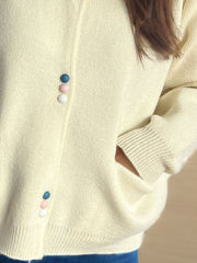 Cream ribbed knit button-up cardigan with pastel buttons and pockets