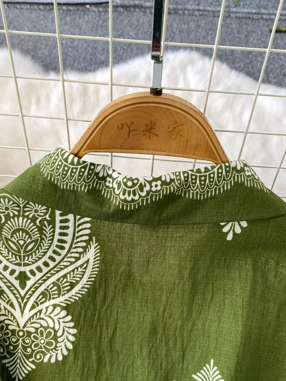 Green collared romper with white paisley print and button details.