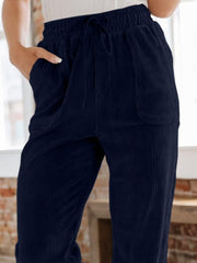 Navy corduroy tapered trousers with drawstring waist and pockets.