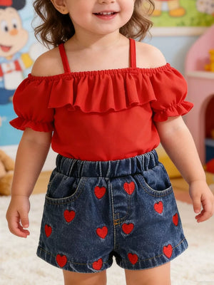 Red off-shoulder ruffled top with puff sleeves and denim shorts with red heart embroidery.