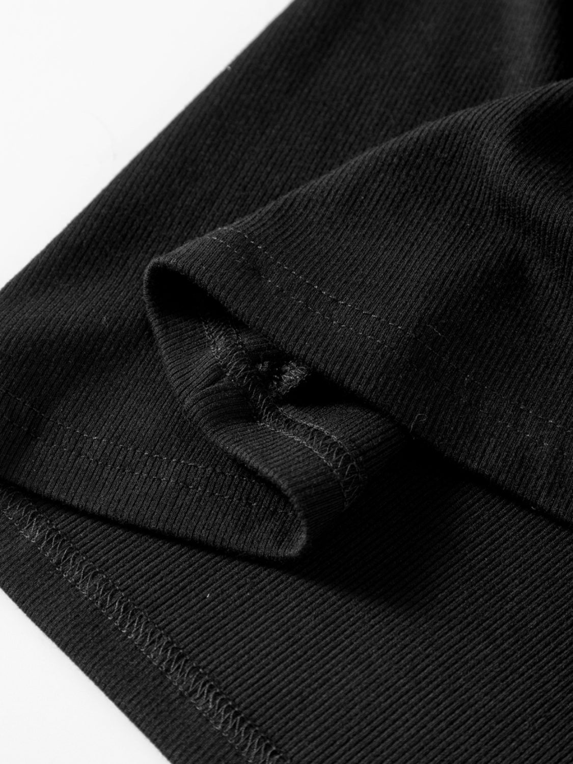 Black ribbed knit long sleeve top with visible stitching detail on cuff.