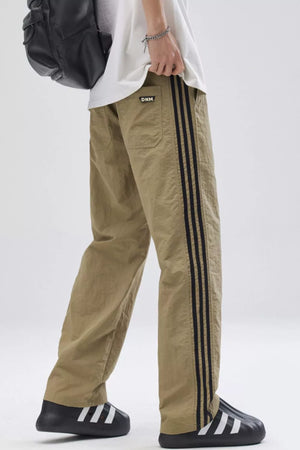 Khaki relaxed fit wide-leg sweatpants with black side stripes and a small logo patch.