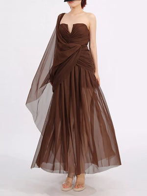 Draped one-shoulder maxi dress in coffee brown with a flowing sheer overlay and ruched bodice.