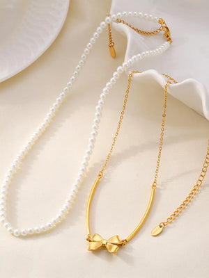 Gold layered necklaces with pearls and a bow pendant