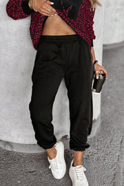 Black lounge pants with elastic waist and cuffed ankles, paired with a burgundy leopard print top.