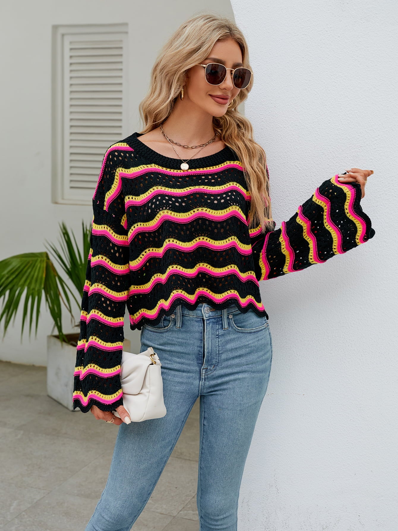 Black scalloped crochet crop sweater with pink and yellow wavy stripes, bell sleeves.