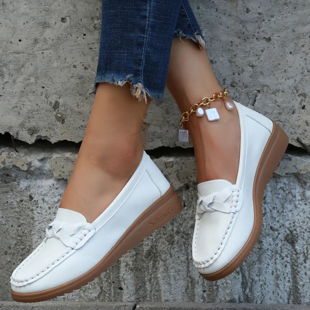 White leather loafers with braided detail and brown sole.