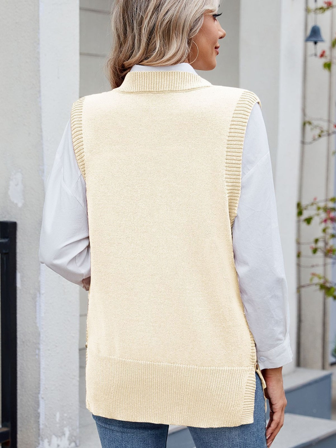 Cream ribbed knit vest with side buttons, worn over a white shirt.