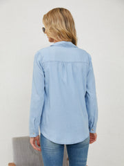 Light wash denim utility shirt with button cuffs and a curved hem.