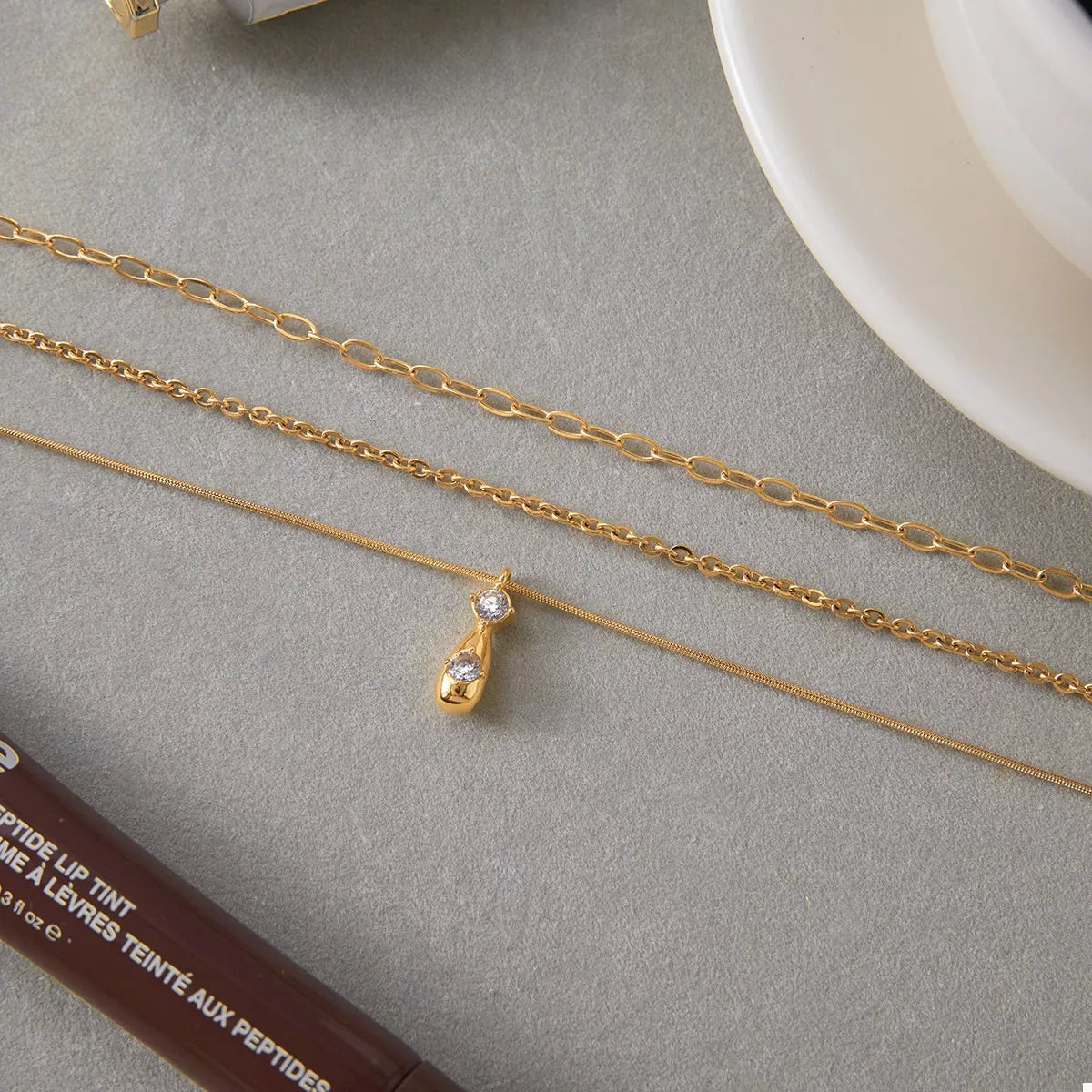 Gold three layered pendant necklace with two clear crystals on a teardrop charm.