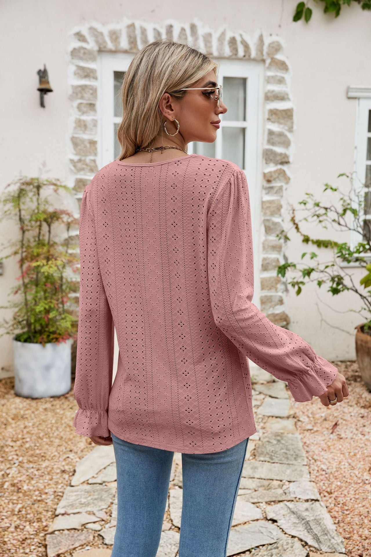 Blush pink eyelet lace blouse with ruffle sleeves and a textured pattern.