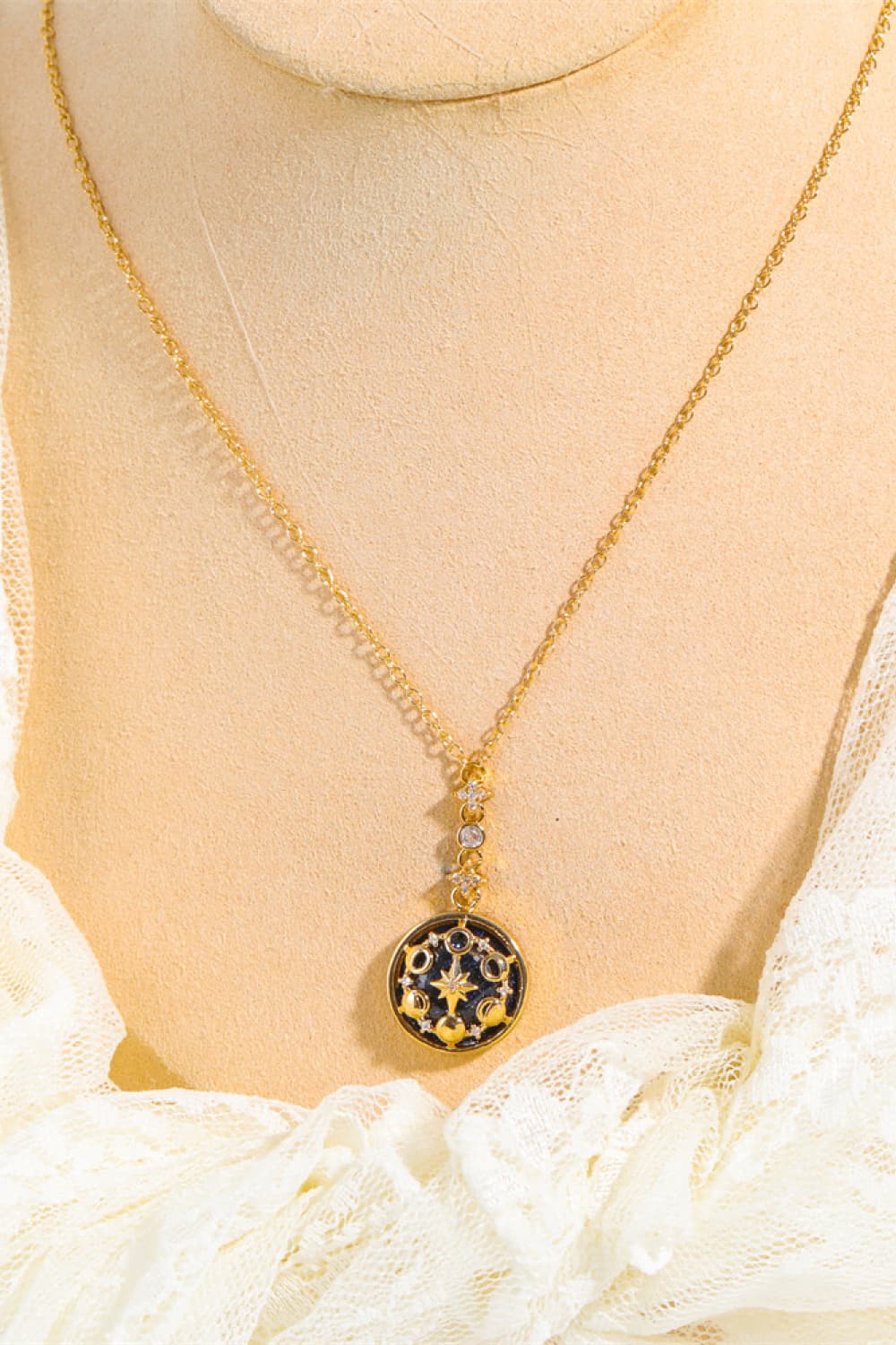 Gold celestial medallion pendant necklace with moon and star details on a delicate chain.
