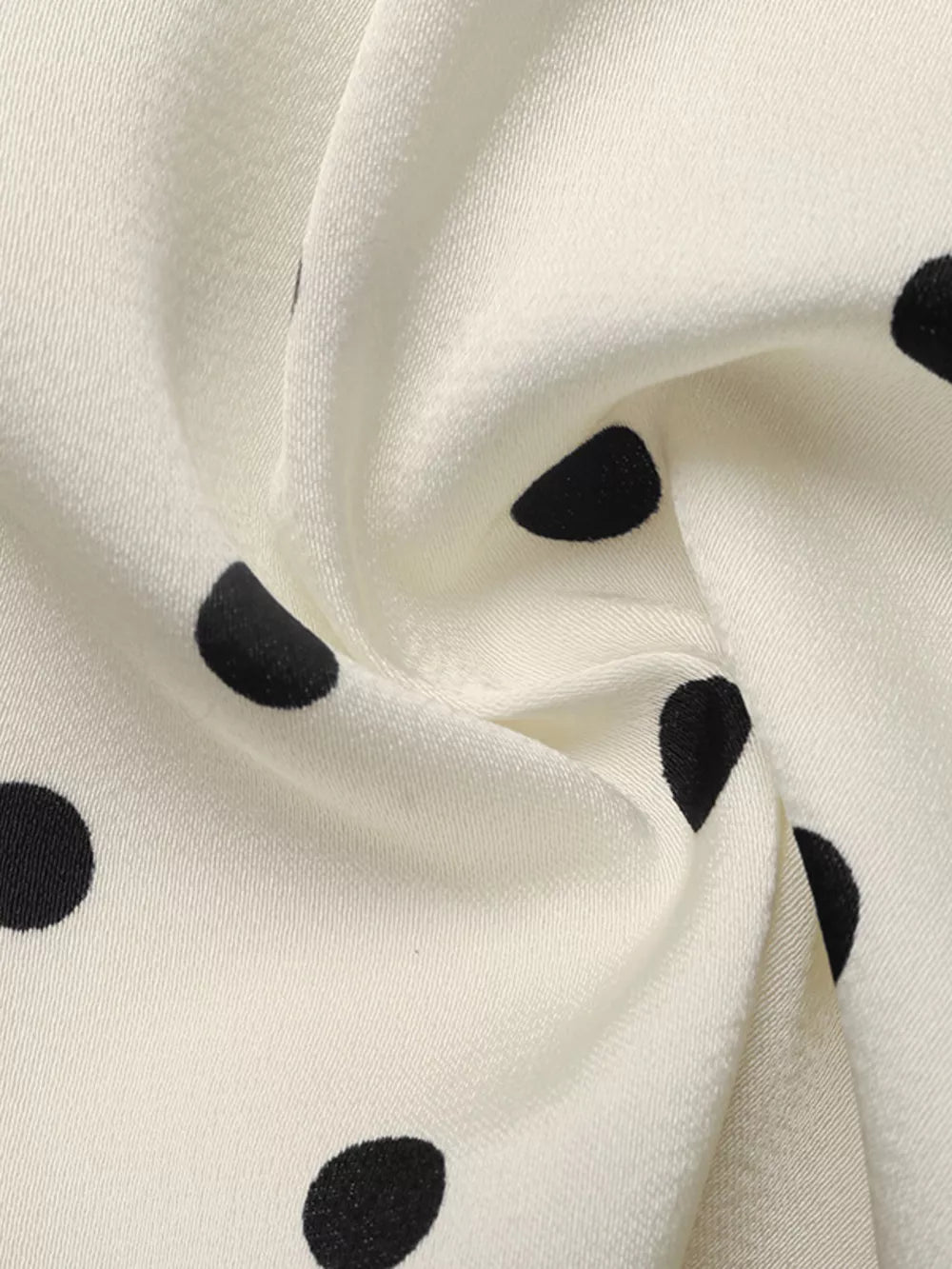 Cream peplum blouse with black polka dots, showing fabric detail.