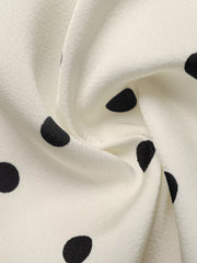 Cream peplum blouse with black polka dots, showing fabric detail.
