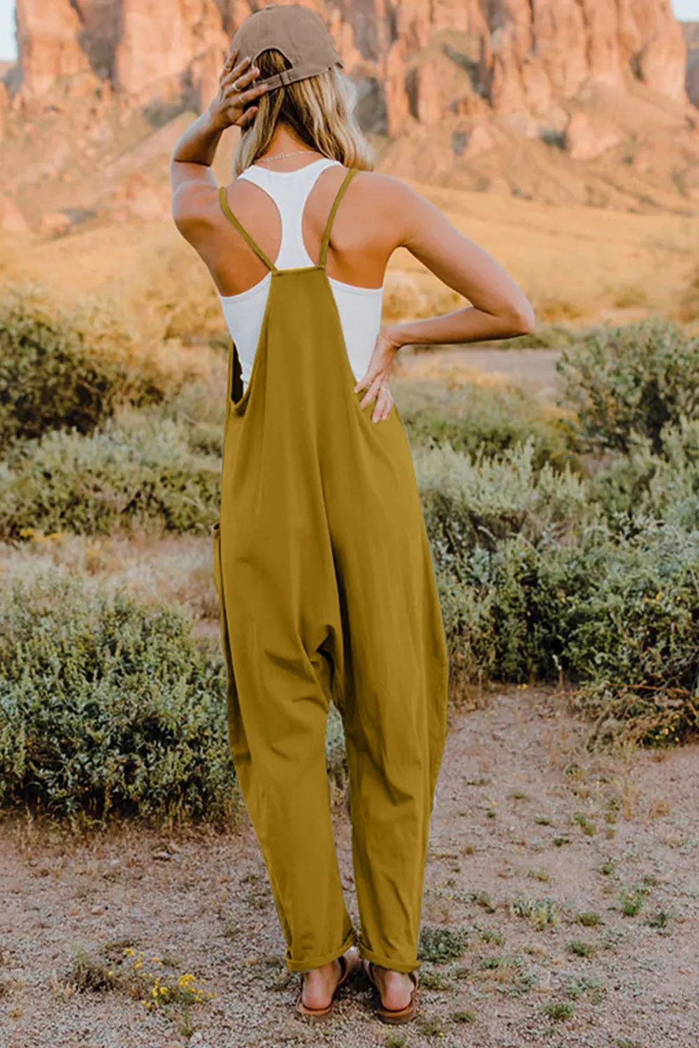 Mustard cotton jumpsuit with wide legs, pockets, and a V-neck, styled with a white tank top.