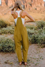 Mustard cotton jumpsuit with wide legs, pockets, and a V-neck, styled with a white tank top.