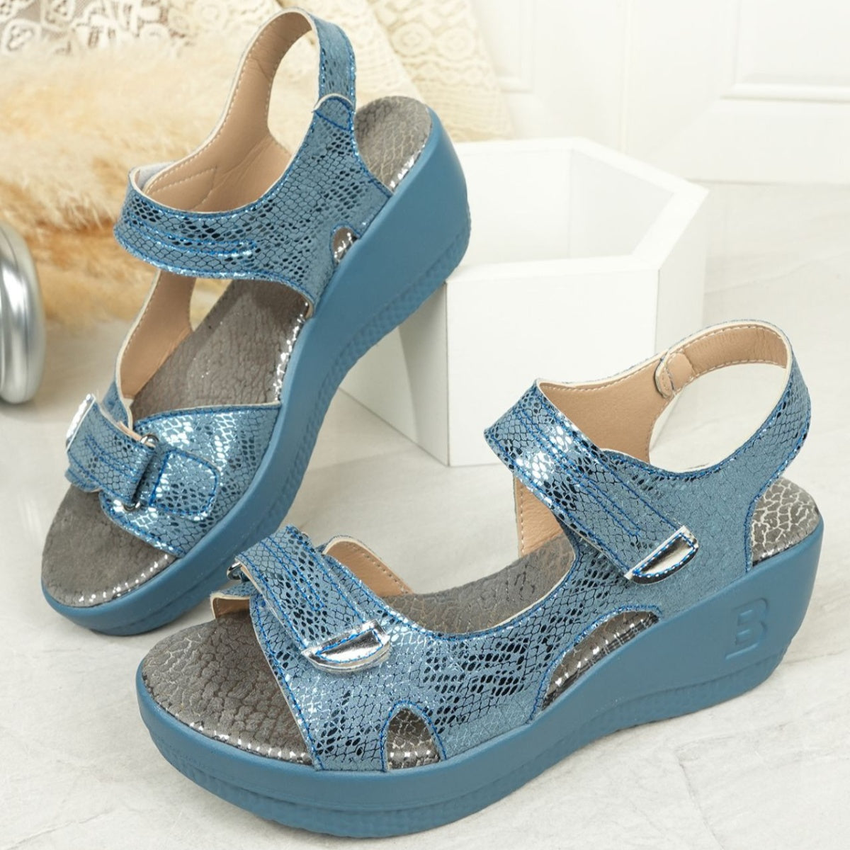 Sky blue textured wedge sandals with adjustable straps and contrast stitching.