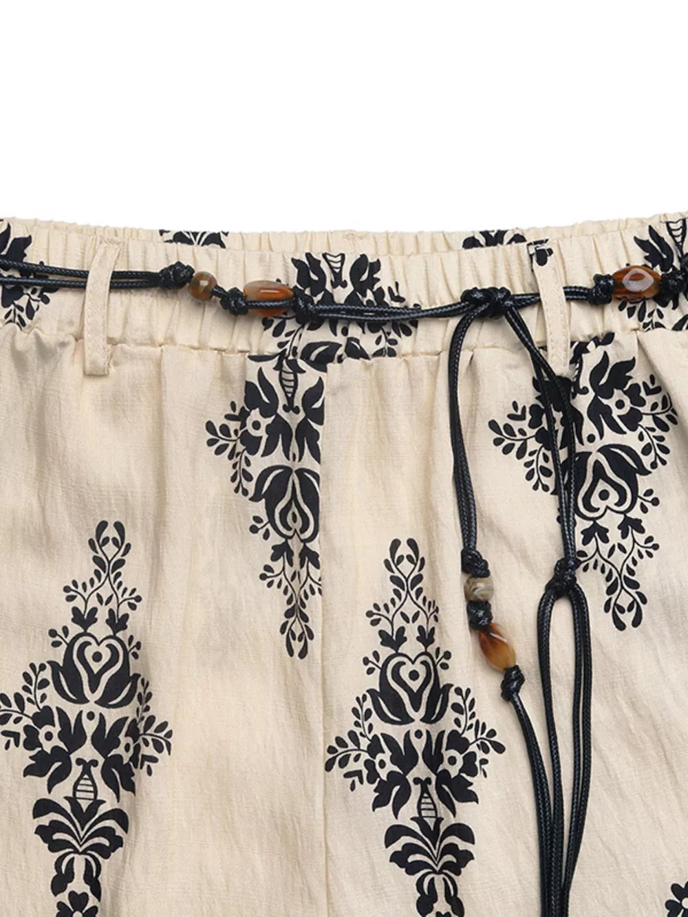 Beige maternity wide leg trousers with black boho print and beaded drawstring.