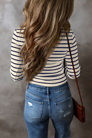 Ribbed stripe long sleeve henley top in cream and navy blue, styled with distressed jeans.