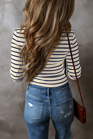 Ribbed stripe long sleeve henley top in cream and navy blue, styled with distressed jeans.