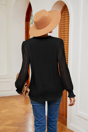 Black V-neck blouse with lace detail on the sleeves and ruffled cuffs.