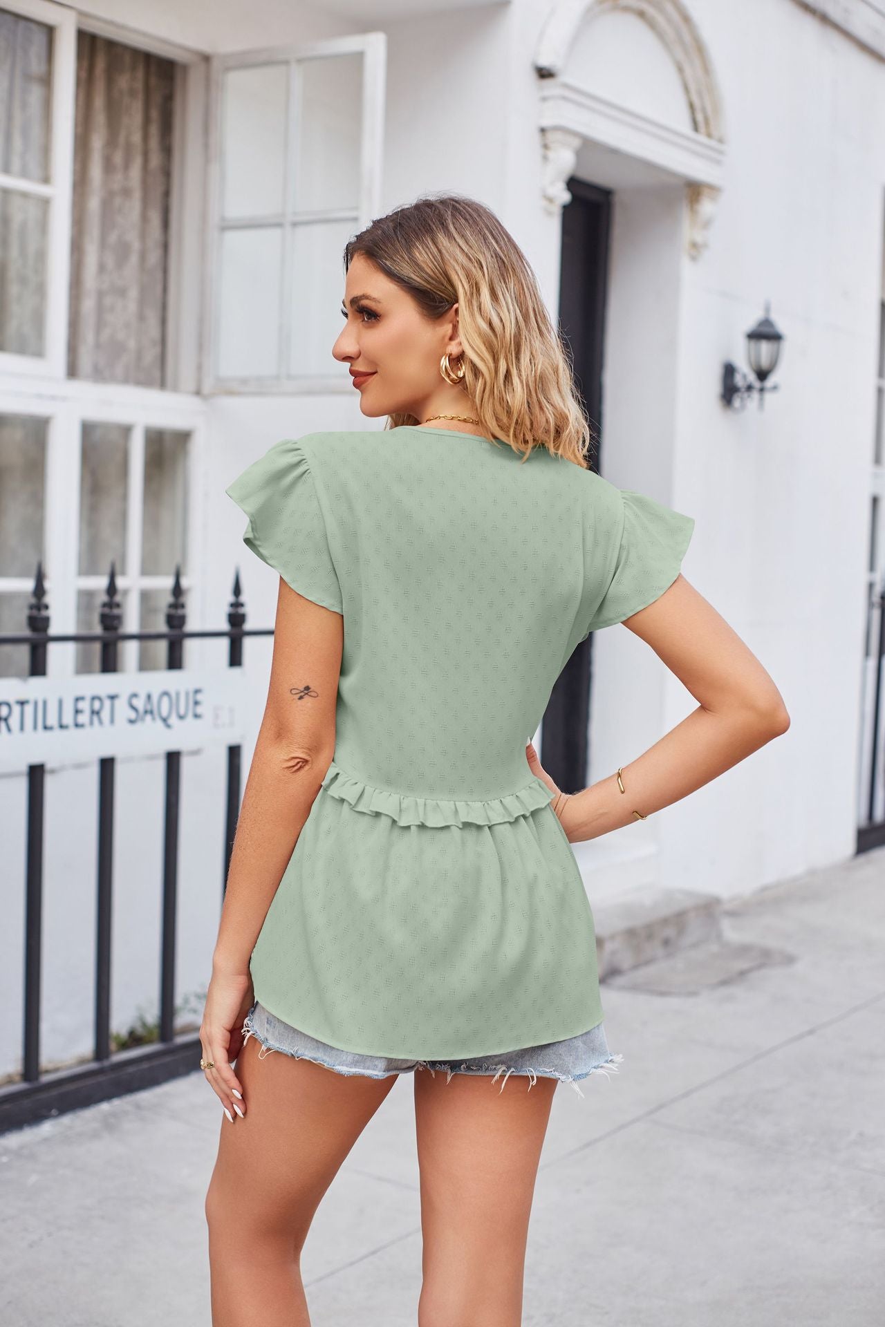 Light green peplum blouse with flutter sleeves and a ruffled hem detail.