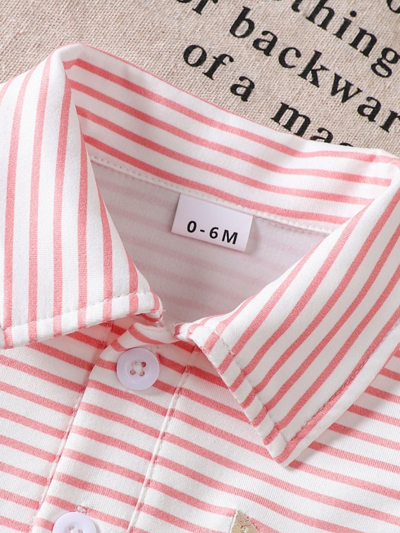 Pink striped polo shirt for baby with classic collar and button detail.