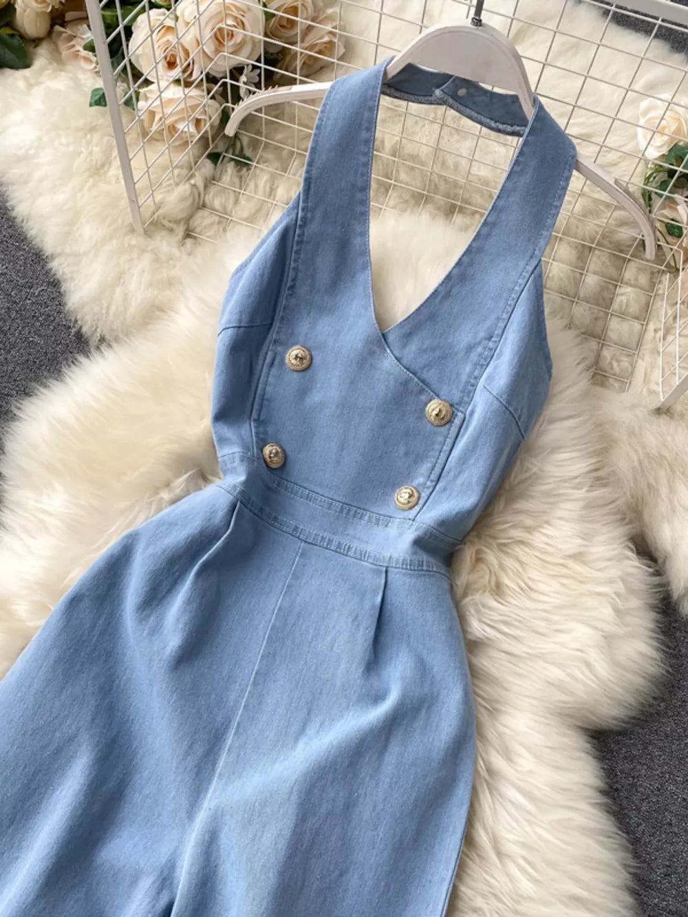 Light blue denim halter jumpsuit with gold button detail and wide legs.