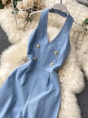 Light blue denim halter jumpsuit with gold button detail and wide legs.