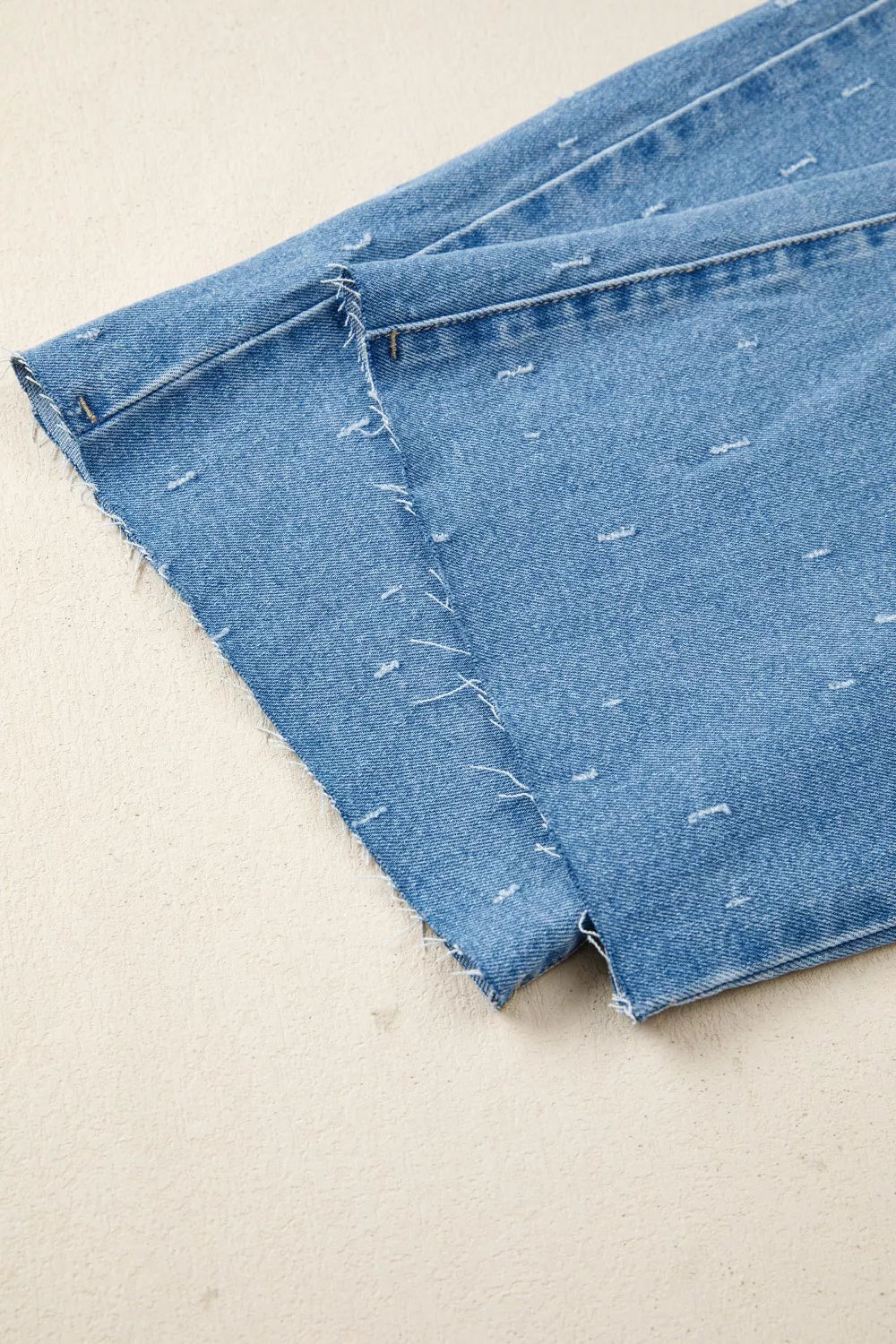 Blue denim jeans with distressed details and raw hem