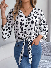 Leopard print tie-front blouse with button detail and bell sleeves.