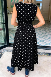 Black polka dot midi dress with smocked waist and ruffled neckline.