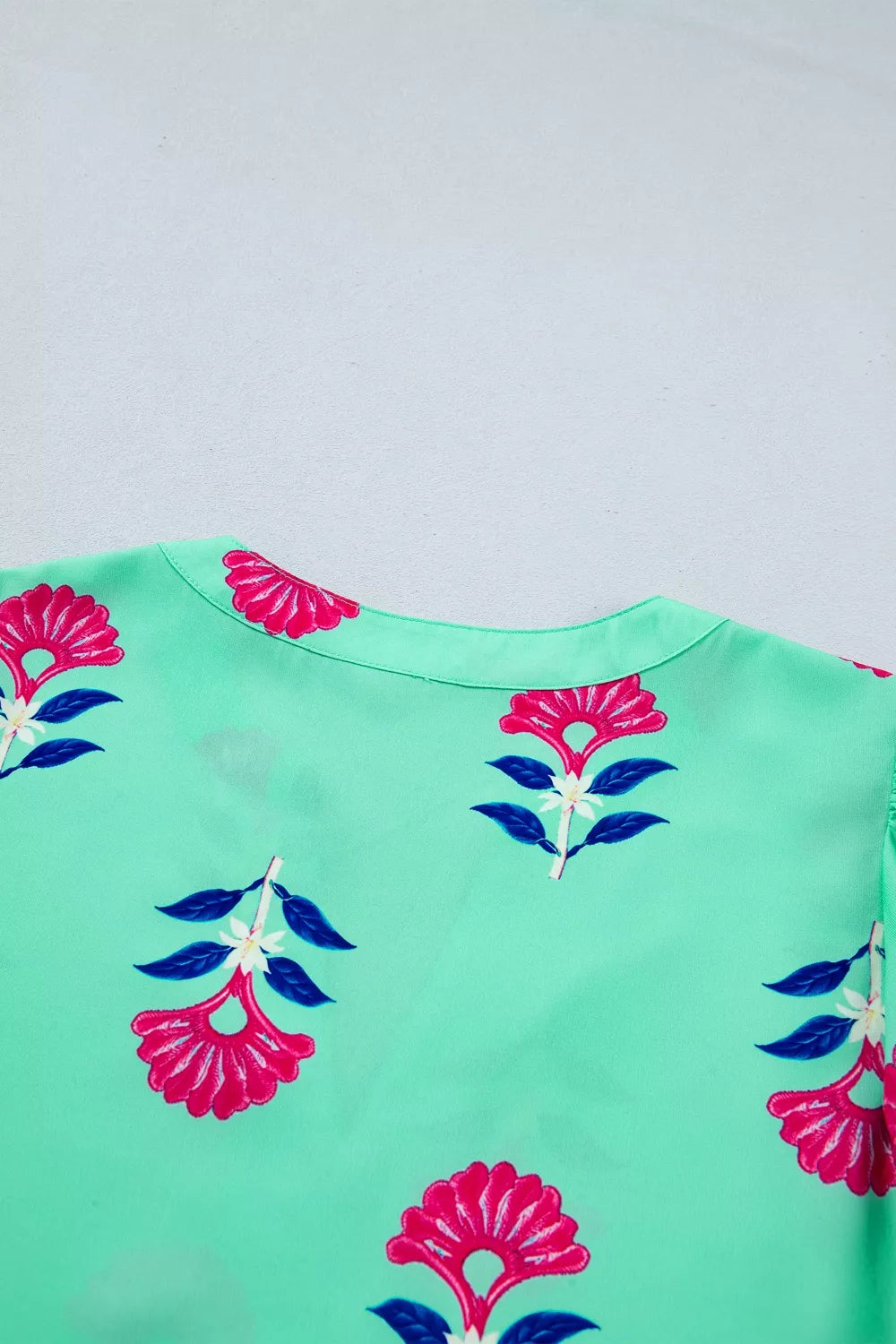 Mint green blouse with embroidered floral print, V-neck, and flutter sleeves.