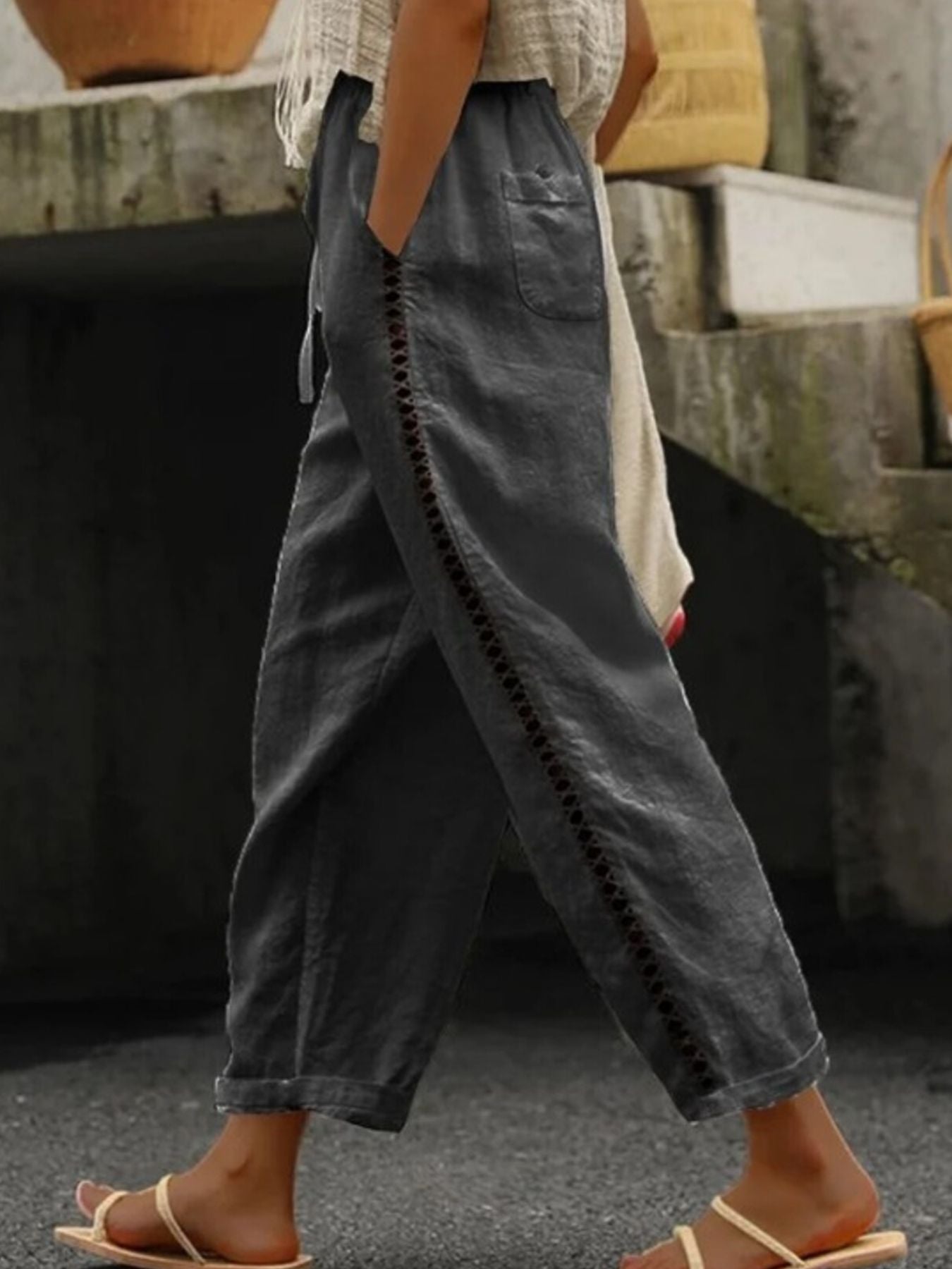 Dark gray relaxed cropped pants with hollow out trim detail and pockets.
