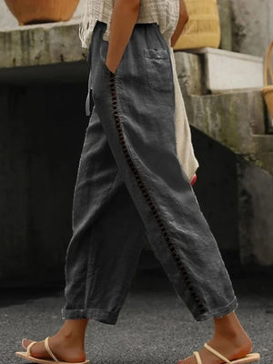 Dark gray relaxed cropped pants with hollow out trim detail and pockets.