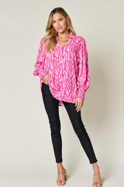 Pink zebra print blouse with shirred cuffs and collar, styled with black pants.