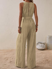 Tan textured wrap-front wide-leg jumpsuit with belted waist and sleeveless design.