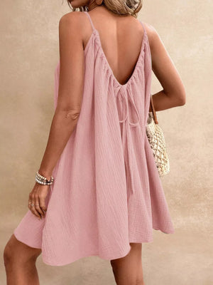 Dusty Pink spaghetti strap mini dress with back tie detail and textured fabric.