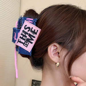 Denim patchwork claw clip with pink "THIS IS ME" patch and drawcord detail.