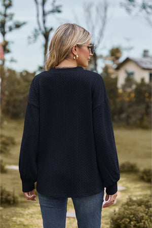 Dark blue textured cable knit v-neck sweater with balloon sleeves.